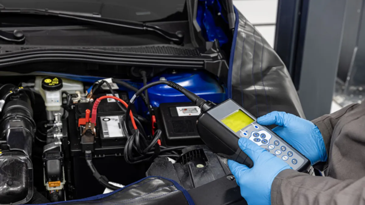 A mechanic using a diagnostic tool to check used hybrid car battery life and overall health during a pre-purchase inspection.