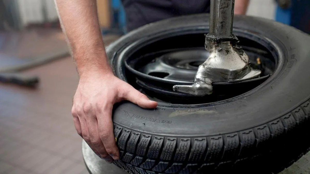 Mechanic using a digital tire wheel balancing machine in an auto repair shop.