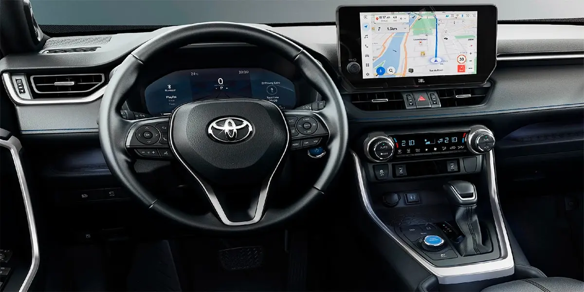 Interior view of a modern Toyota Corolla showing the digital gauge cluster, leather steering wheel, and infotainment screen.