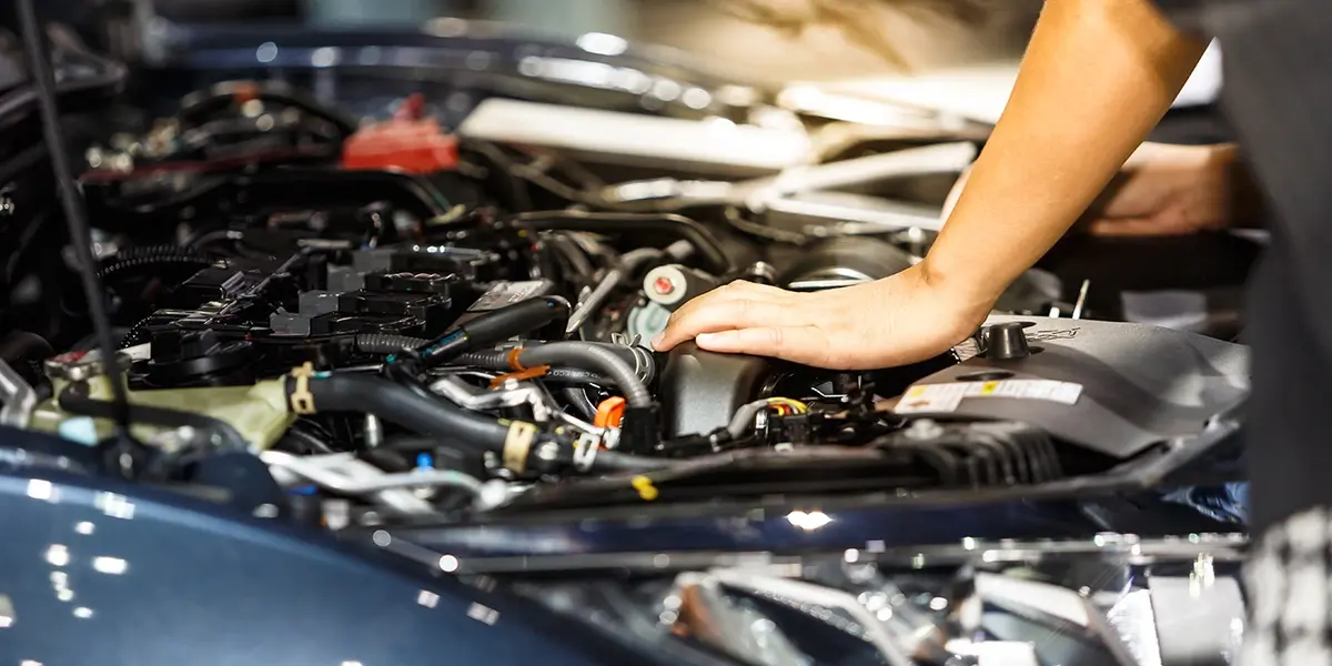 Mechanic inspecting the engine bay and fluid levels of a used Toyota Corolla