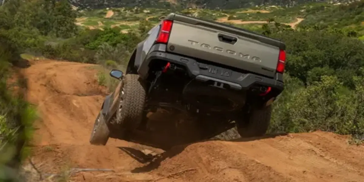 Toyota Tacoma Trailhunter parked on an off-road trail showcasing all-terrain tires and rugged equipment.