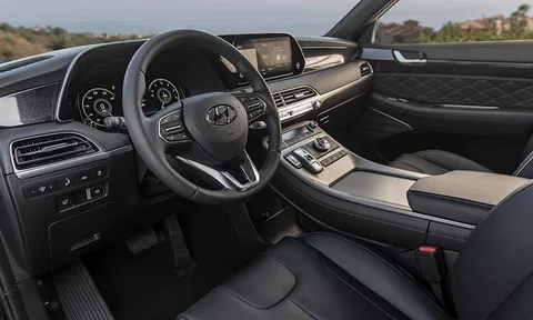 The interior dashboard and front seat area of a Hyundai Palisade featuring a leather-wrapped steering wheel, digital instrument cluster, and floating center console.
