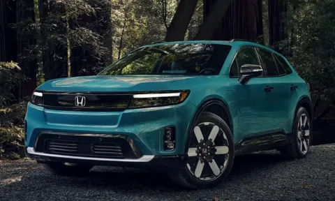 A bright teal Honda Prologue electric SUV parked on a gravel trail in a forest.