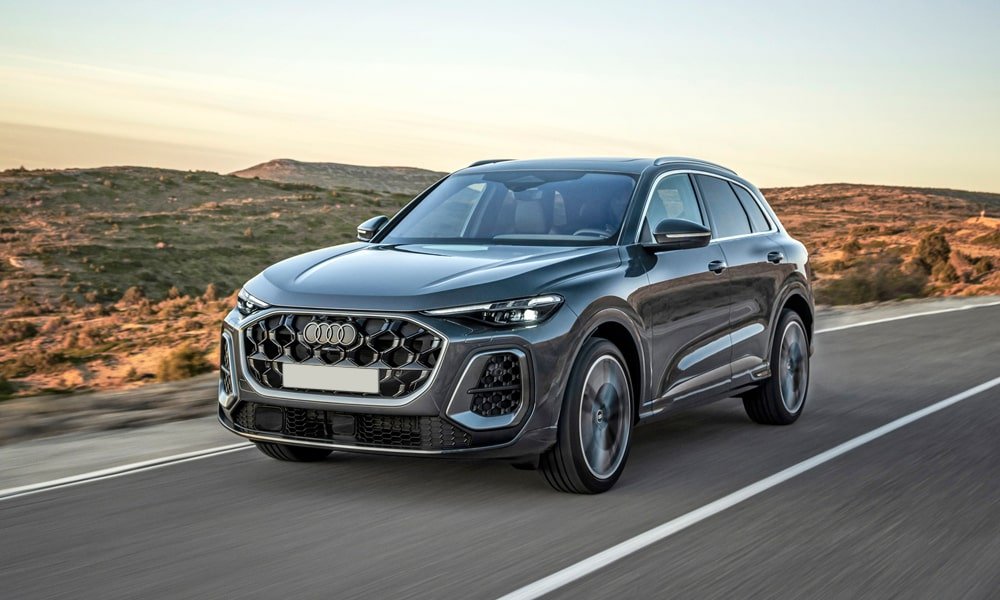 Front three-quarter view of a metallic grey Audi Q5 driving on an open road.