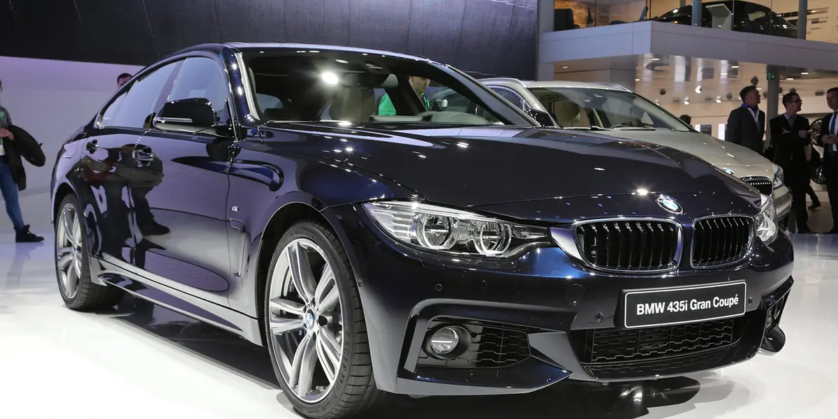 Front three-quarter view of a dark blue BMW 4 Series Gran Coupe on display at an auto show