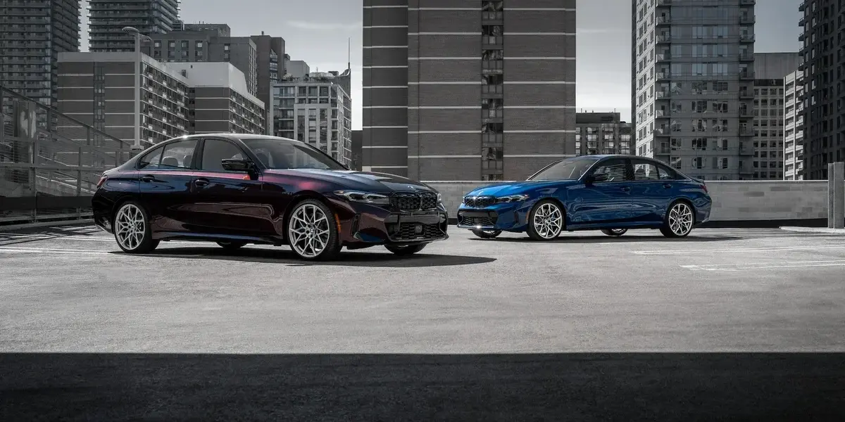 Two BMW M Performance sedans parked on a rooftop lot against a city skyline.