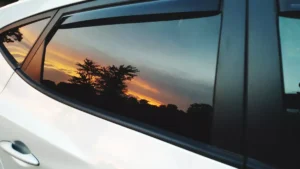 Professional car window tinting on a modern sedan parked in daylight showing dark tinted side windows. How Much to Tint Car Windows: 15+ Cost Factors and Pricing Tips