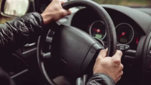 Driver holding a steering wheel experiencing vehicle vibration on the road.
