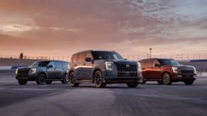 Three midsize SUVs lined up on a racetrack at sunset, with a dark SUV in the center and two SUVs behind it on either side.